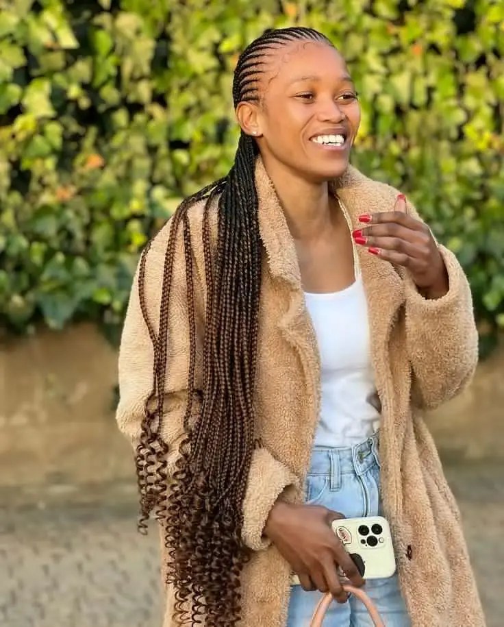A woman rocking a version of the waist-length Ghana weave style with curls at the ends.