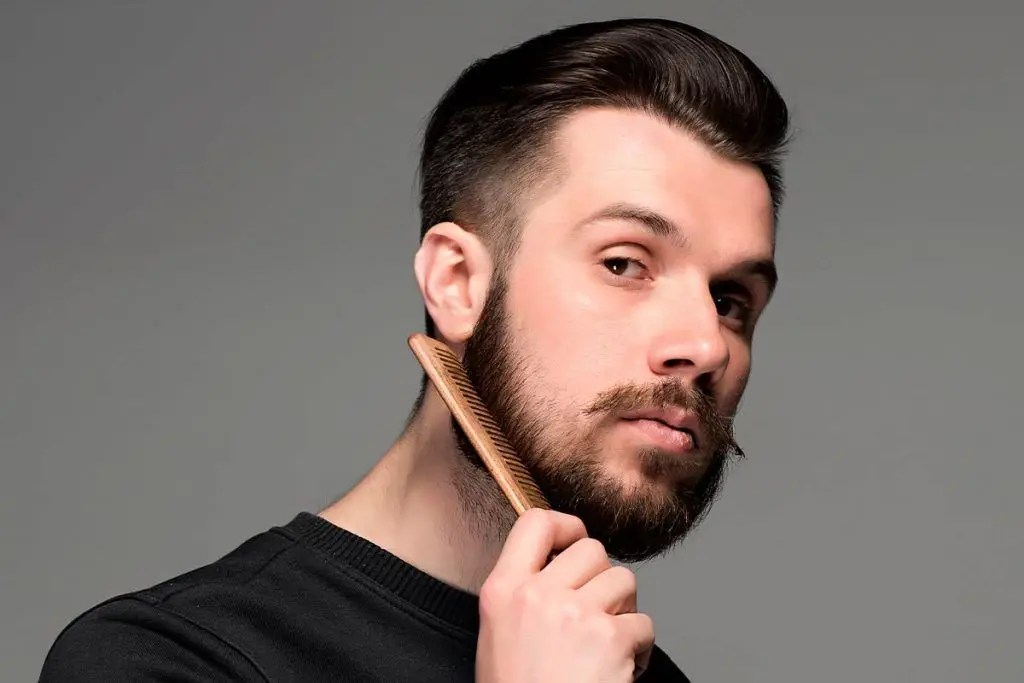 Handsome man combing his beard on his neck.