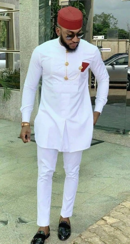 Actor wearing a white caftan with a red wart hat
