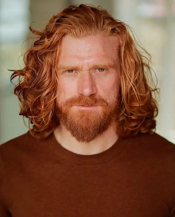 man with long hair showing off beard