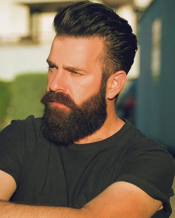 A man with his hair pulled back shows off his beard.