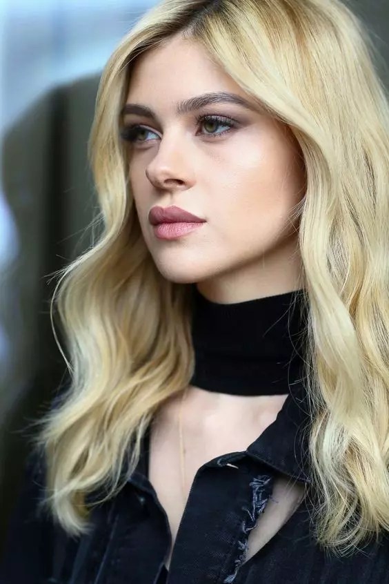 Nicola Peltz rocks a mid-part style with blonde wavy hair.