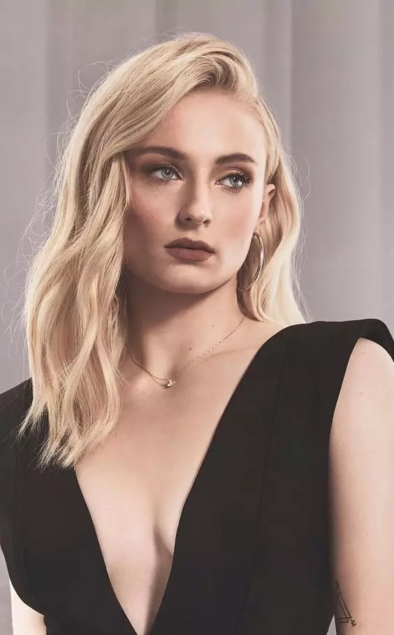 Sophie Turner shows off her blonde beauty in a side-parted wave style.