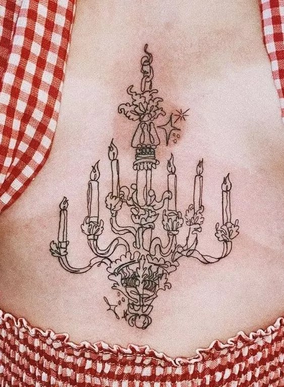 A woman shows off a chandelier-inspired sternum tattoo