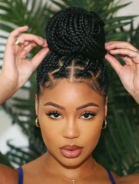 A woman wraps a beautiful braid in a bun.