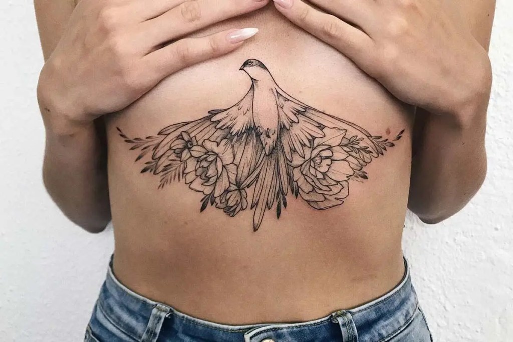 A woman shows off a tattoo of an eagle design on her breastbone