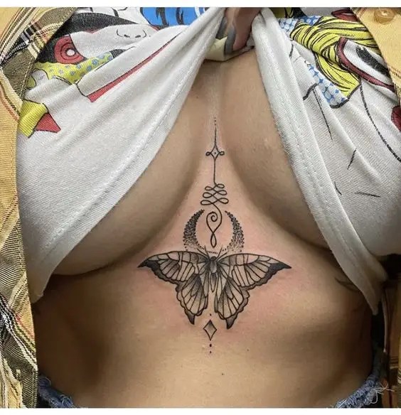 A beautiful woman shows off her moth sternum tattoo design.