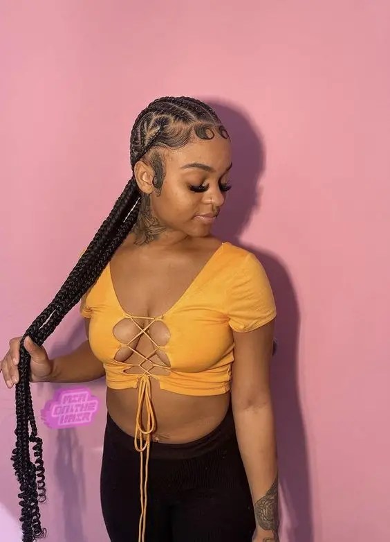 A pretty woman in a crop top rocking long cornrows