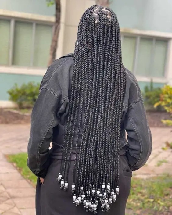 Woman showing back view of unknotted braids decorated with beads