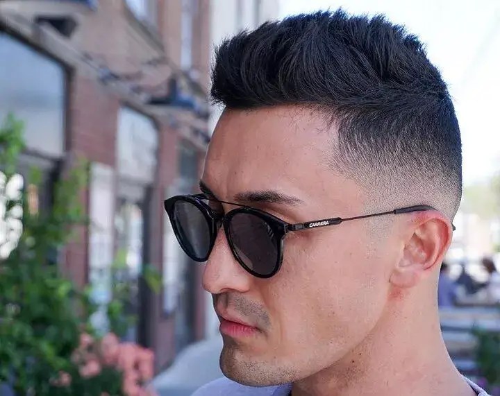 The man rocks a mid-fade comb over a tinted hairstyle