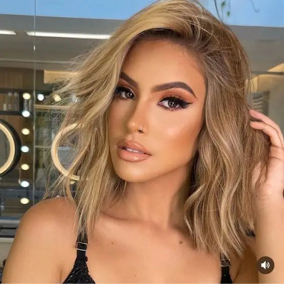 A beautiful woman shows off her short dirty blonde hair with blonde highlights.