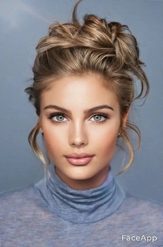 A beautiful woman shows off her dirty blonde hair wrapped in a disheveled bun.