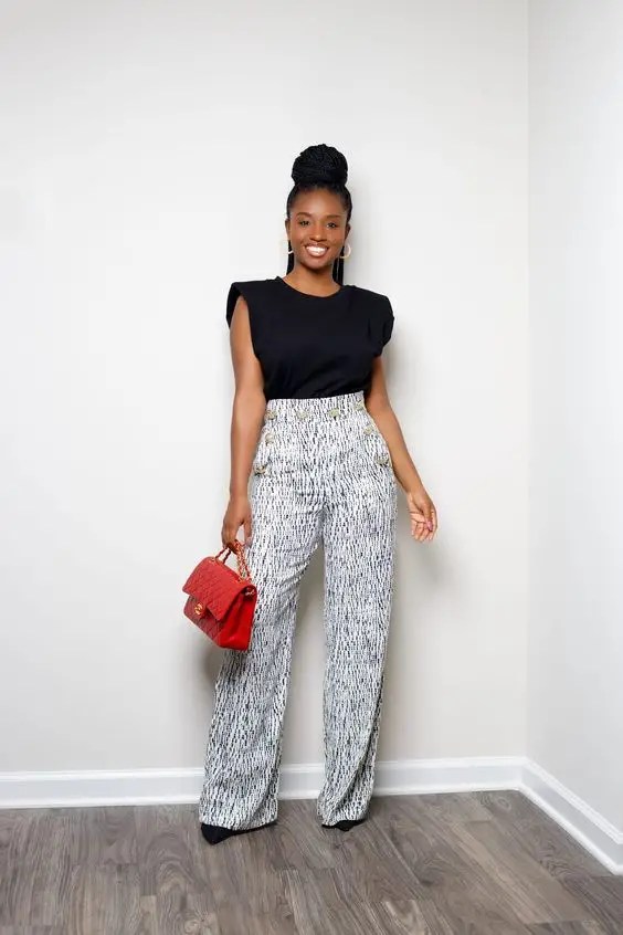 A woman in a palazzo with a cute top and a red handbag