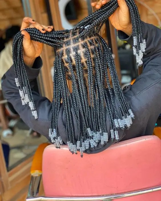 Woman showing back view of un-knotted braids of beads