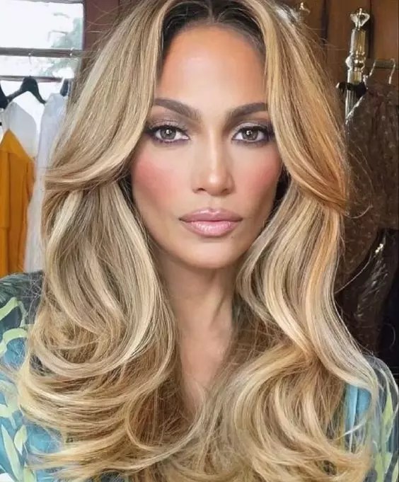Jennifer Lopez shows off the center of her dirty blonde hair parted in waves.