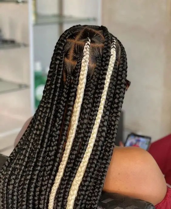 Rear view of a woman showing off her medium knotted braids with black and white extensions