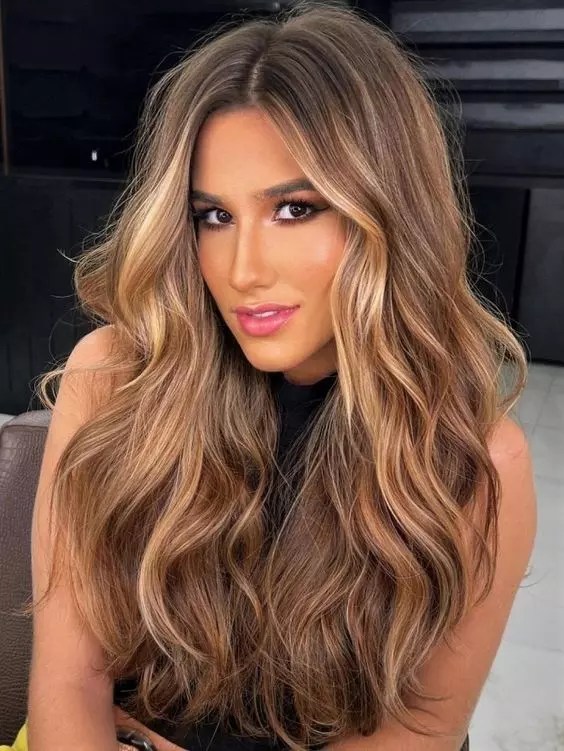 Gorgeous woman show her long hair with blonde highlights.