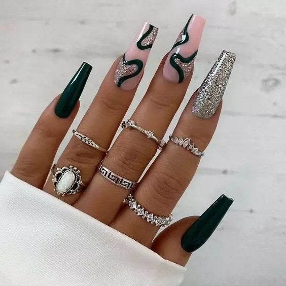 Beautiful nail art combined with army green nail polish, silver glitter and rings.