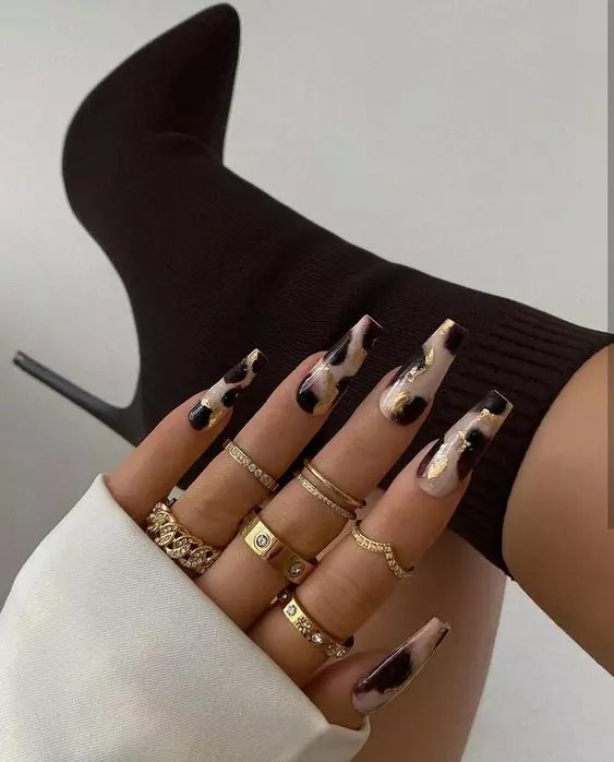 A ring is combined with a beautiful gold and black cute nail design.