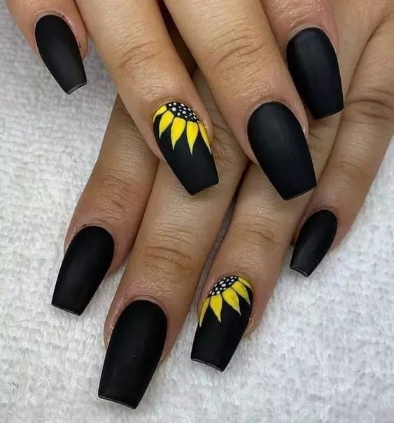 A matte black nail with a leaf print is a cute nail design.