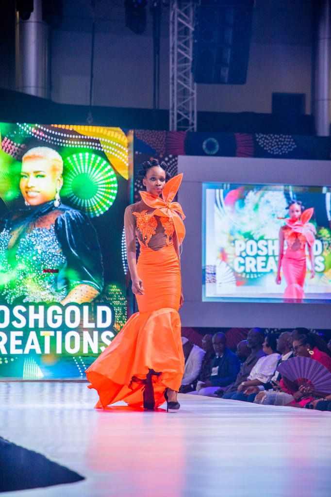 A model walking the runway in a bright orange dress at a fashion show