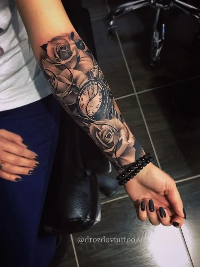 flower and clock sleeve tattoo on a lady's arm