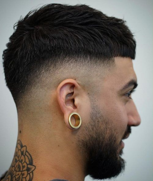 Tattooed man with short hair and beard fading wearing earrings