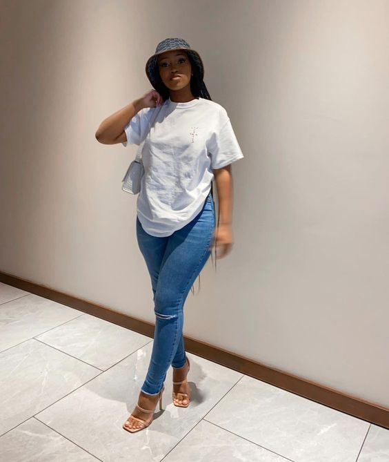 Woman wearing white tee and blue jeans and bucket hat