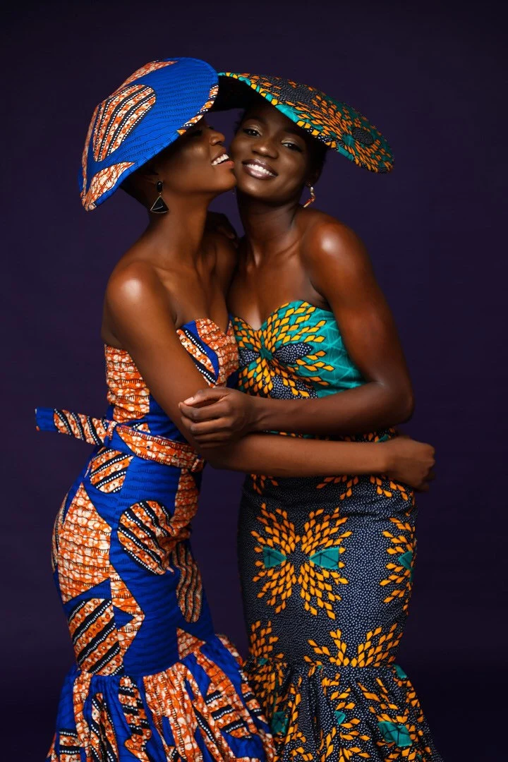 Smiling sisters in matching dresses and ankara hats