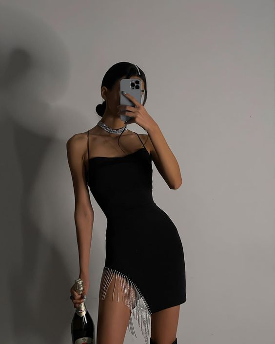 Woman in a little black dress taking a selfie in the mirror