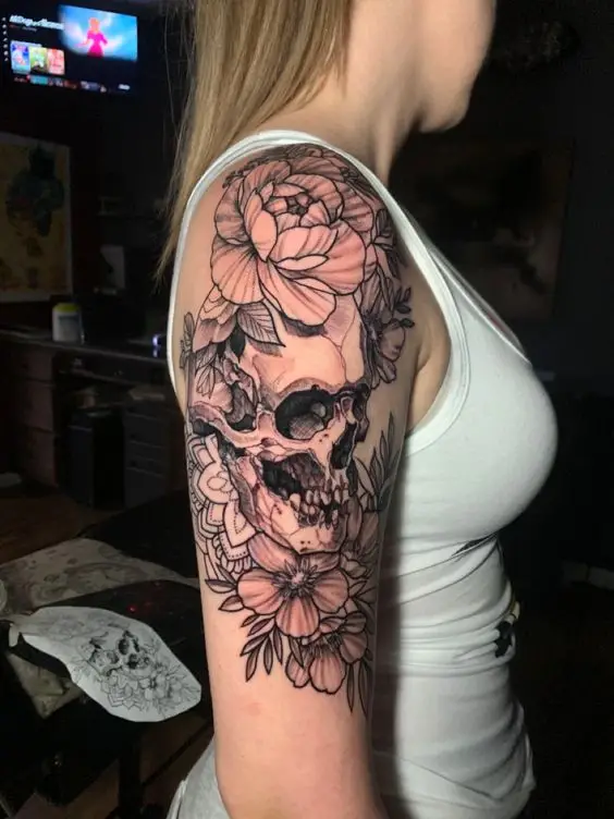 lady in white singlet wearing skull and flowers sleeve tattoo