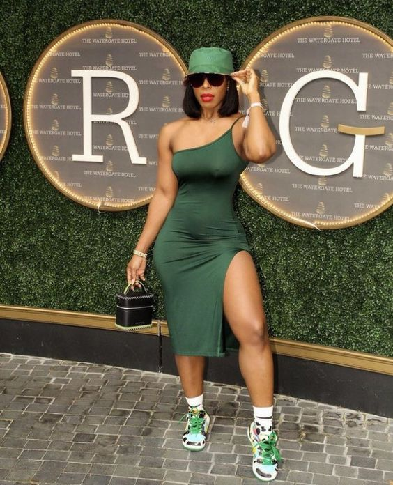 Woman wearing green bucket hat with dark green dress and sneakers