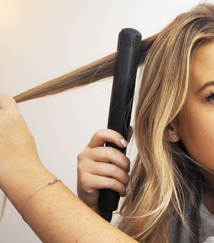 Photo of a woman trying to wave her hair with a hair straightener