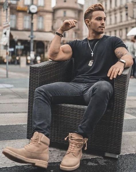 A man in black jeans and a black t-shirt with Timberland boots and chains