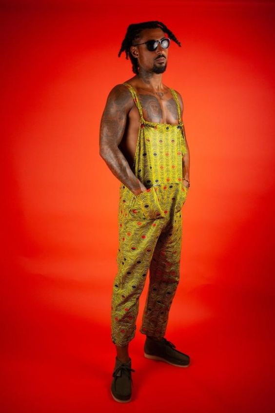 Man with tattoo and dreads wearing ankara dungarees