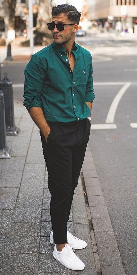 A man wearing a green shirt and pants, a black shade and white shoes