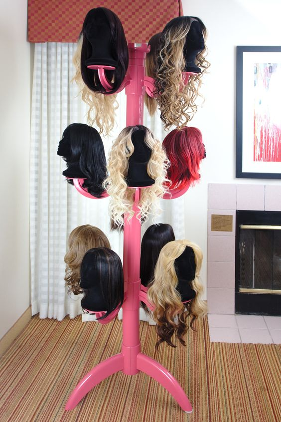 Various hair wigs on pink wig stand