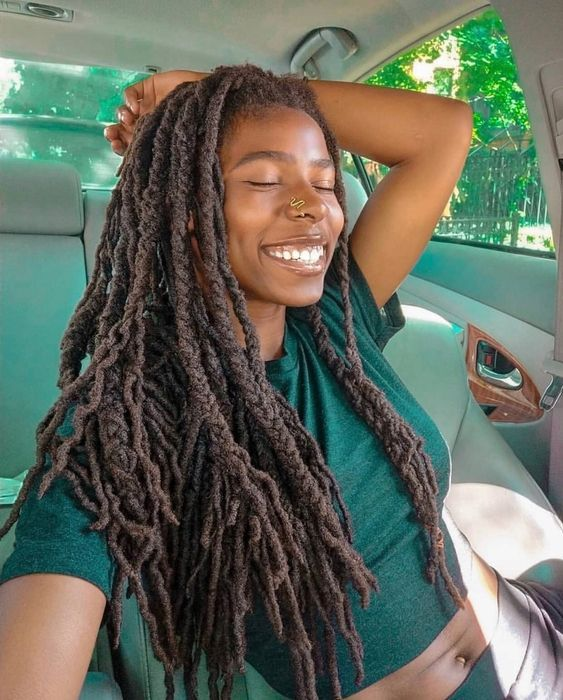 Smiling woman wearing dreadlocks with extensions in car